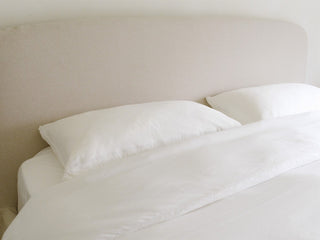 A made bed dressed in eucalyptus lyocell sheets and pillows in a bright, minimal bedroom