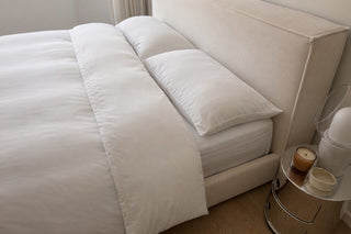 Silk vs satin pillowcase comparison, smooth white eucalyptus lyocell pillowcases on a made bed in soft daylight