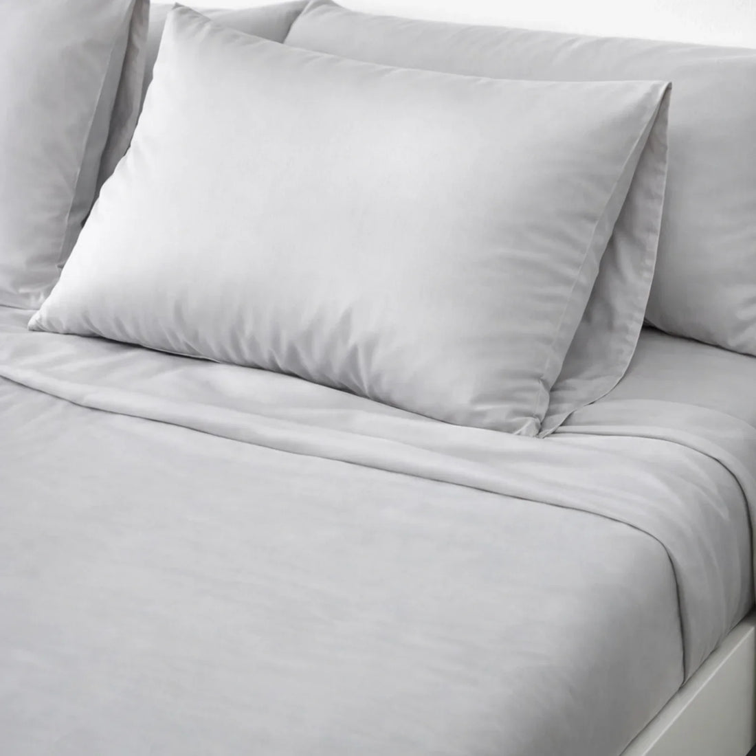 Two Gentle Slate CloudThera eucalyptus lyocell pillowcases on a made bed, the low-friction sleep surface that determines acne mechanica load overnight