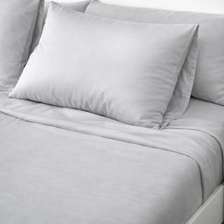 Two Gentle Slate CloudThera eucalyptus lyocell pillowcases on a made bed, the low-friction sleep surface that determines acne mechanica load overnight