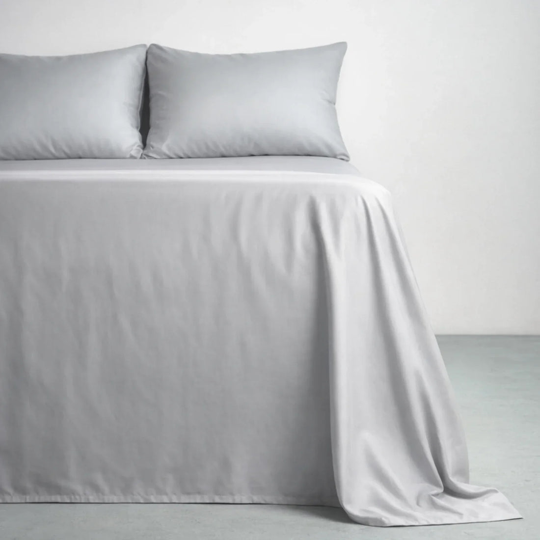 Gentle Slate eucalyptus lyocell sateen sheets on a made bed, the smooth low-luster surface at the center of the percale vs sateen question