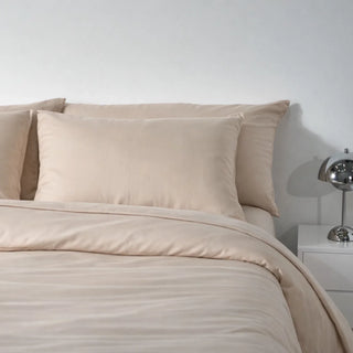 A bed made up in Soft Cashmere eucalyptus lyocell pillowcases, the surface one side of the face presses into all night