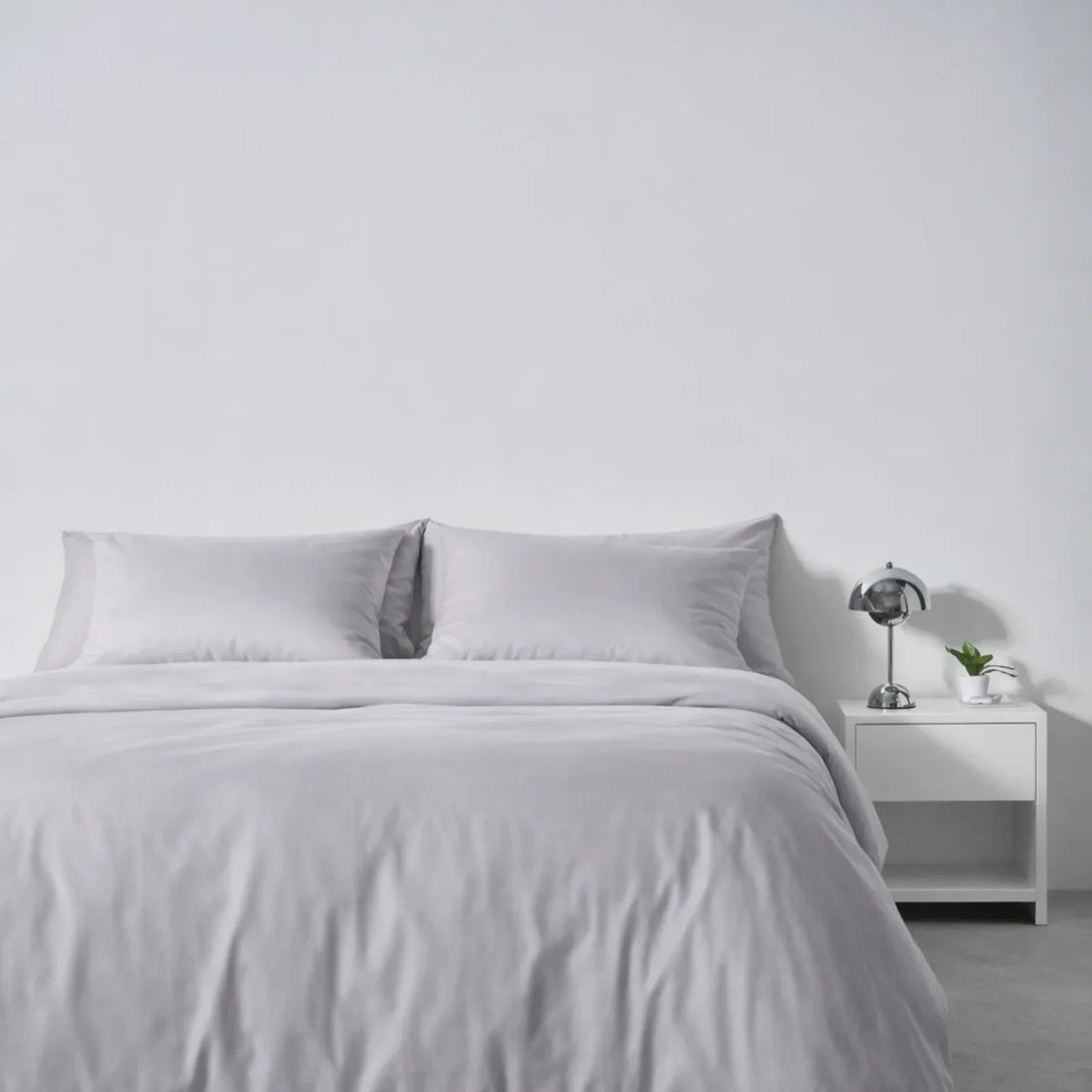 A made bed in Gentle Slate eucalyptus lyocell, set up for training yourself to sleep on your back
