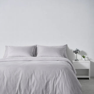 A made bed in Gentle Slate eucalyptus lyocell, set up for training yourself to sleep on your back