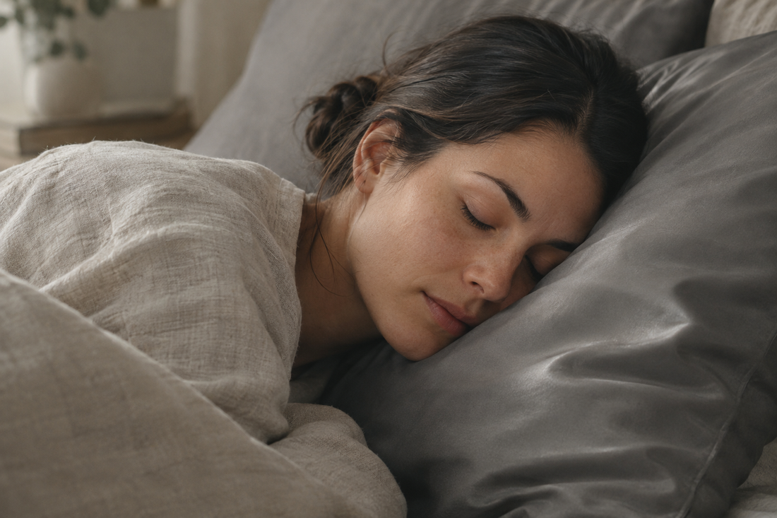 Woman with dark hair in a low bun asleep with her temple and hairline resting on a Gentle Slate eucalyptus lyocell pillowcase, the surface a scalp prone to acne rests on for 8 hours