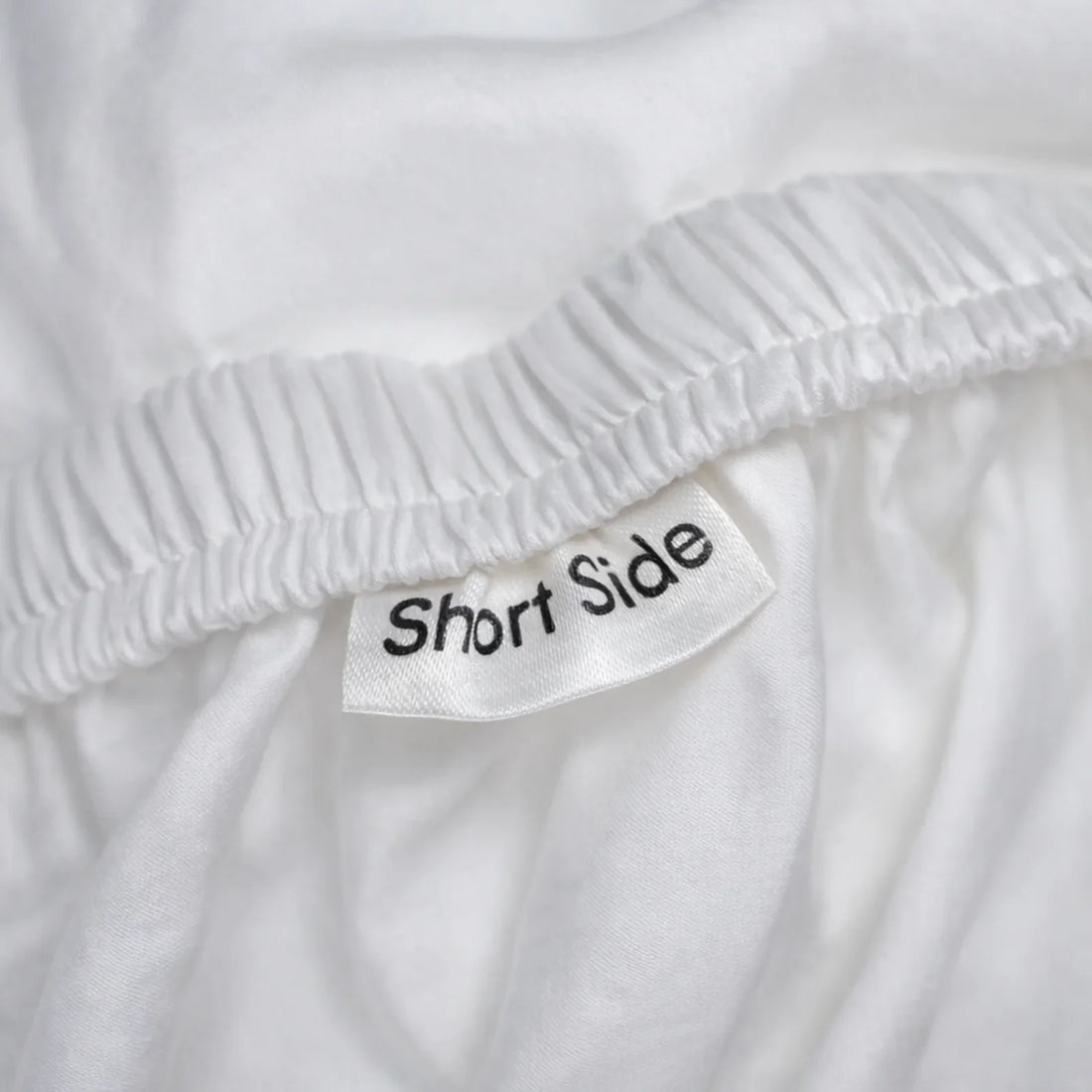 Close-up of a eucalyptus lyocell fitted sheet edge and sewn-in fabric tag, the only place a bedding fiber is named