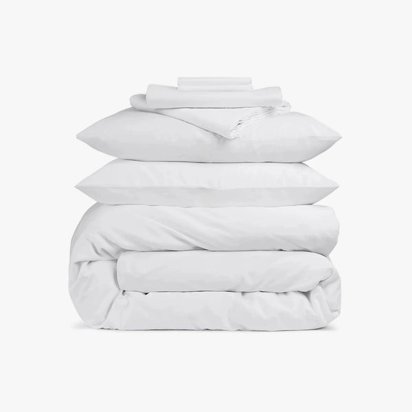 Stack of white bedding including a duvet and pillows on a white background