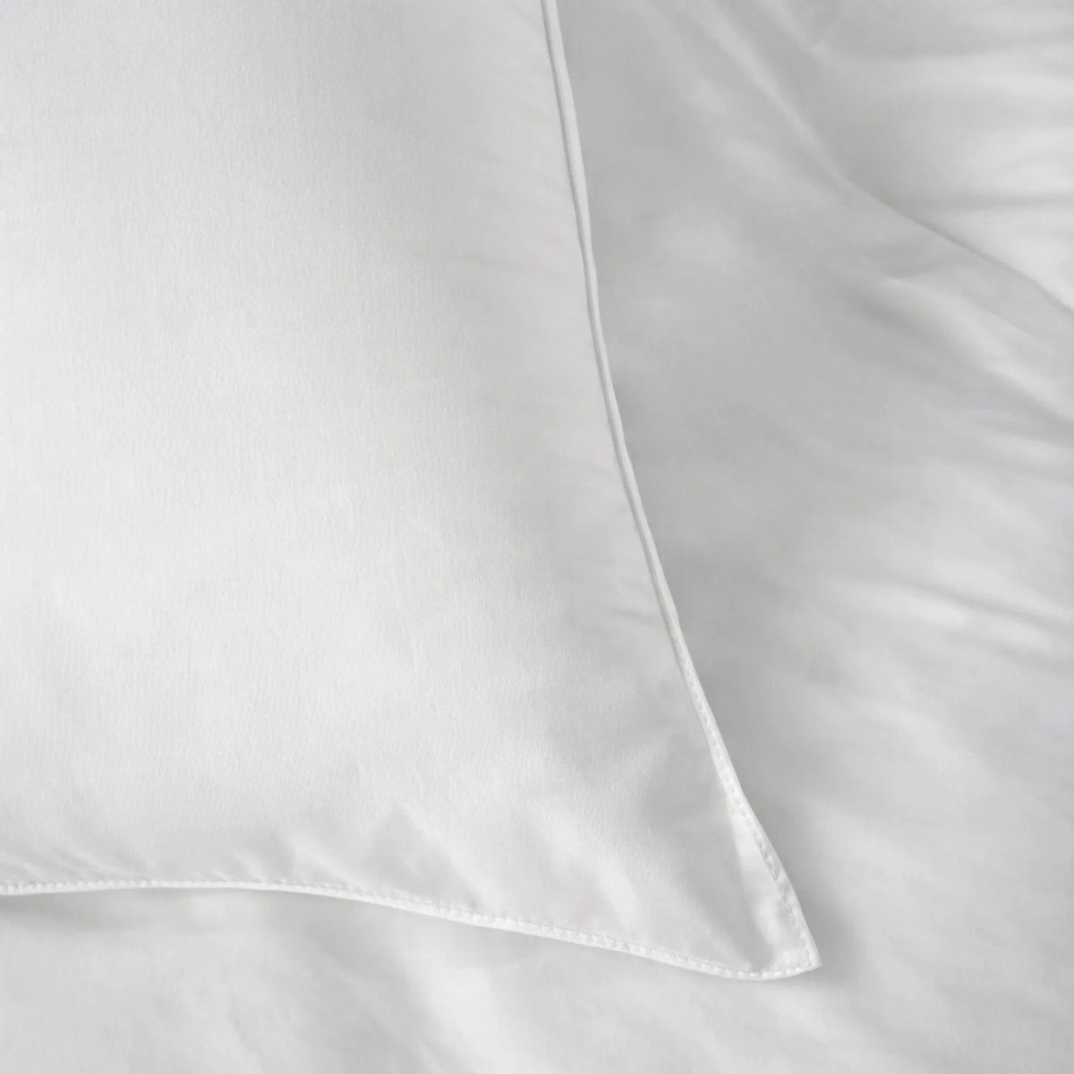 Buttercream eucalyptus duvet and pillows against a linen headboard beside a styled nightstand