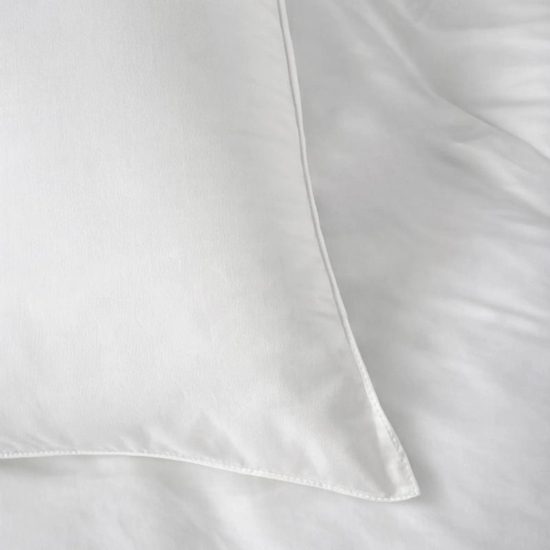 Buttercream eucalyptus duvet and pillows against a linen headboard beside a styled nightstand